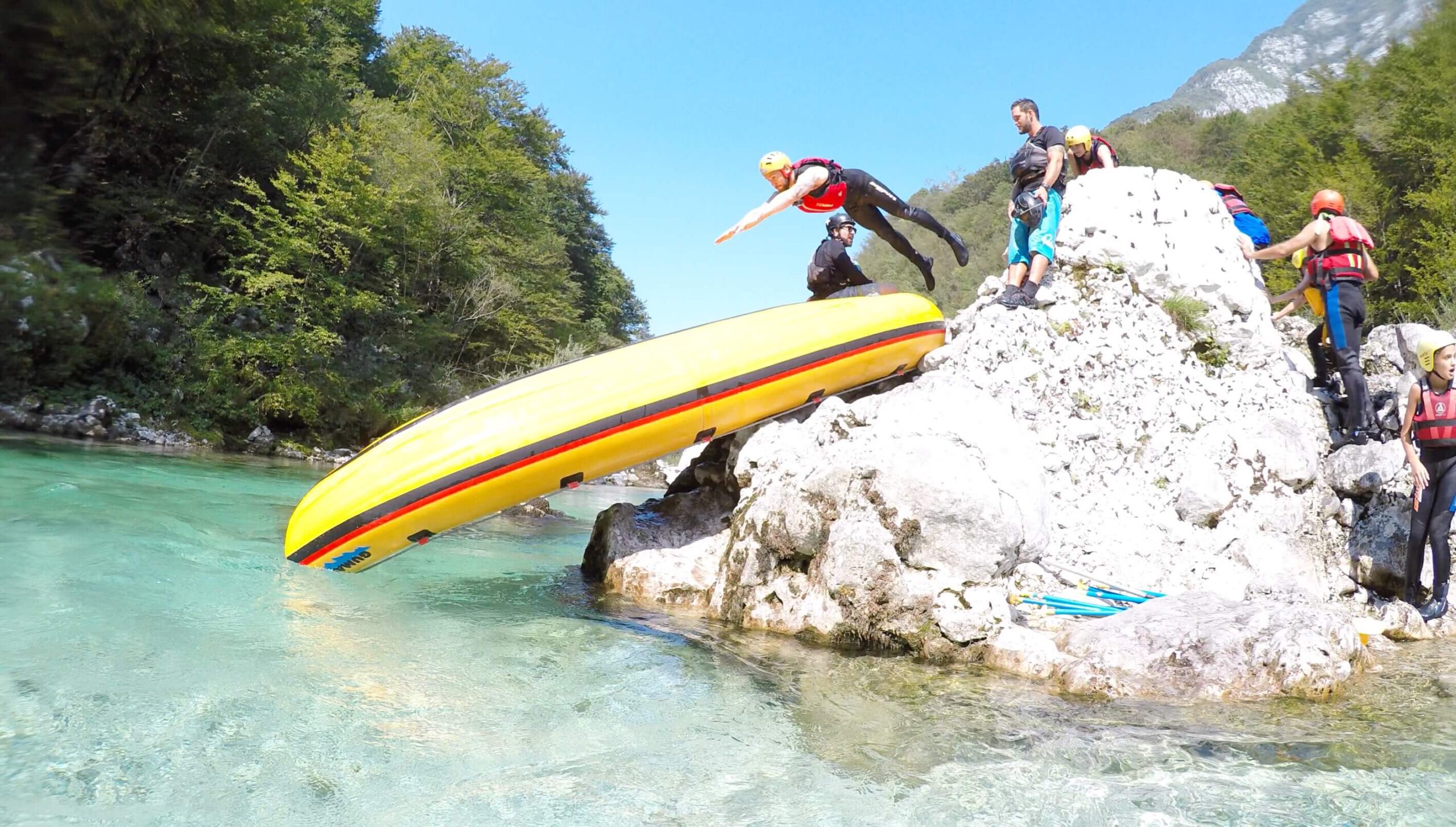 Alex jumping down upturned raft used as a slide, Soca River, Slovenia